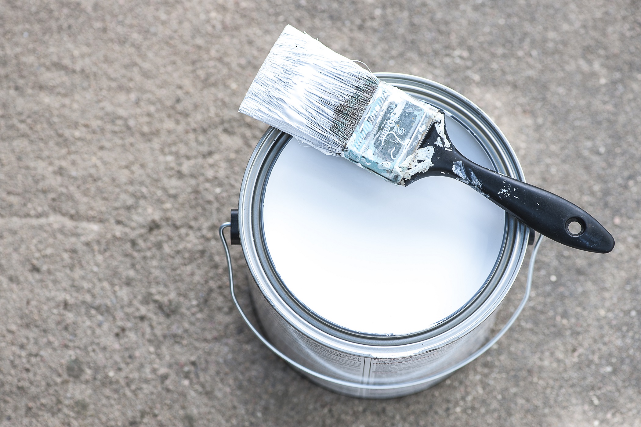 aluminium paint can with white paint and dirty paint brush
